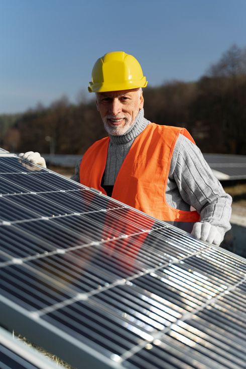 profesional con casco al lado de placa solar